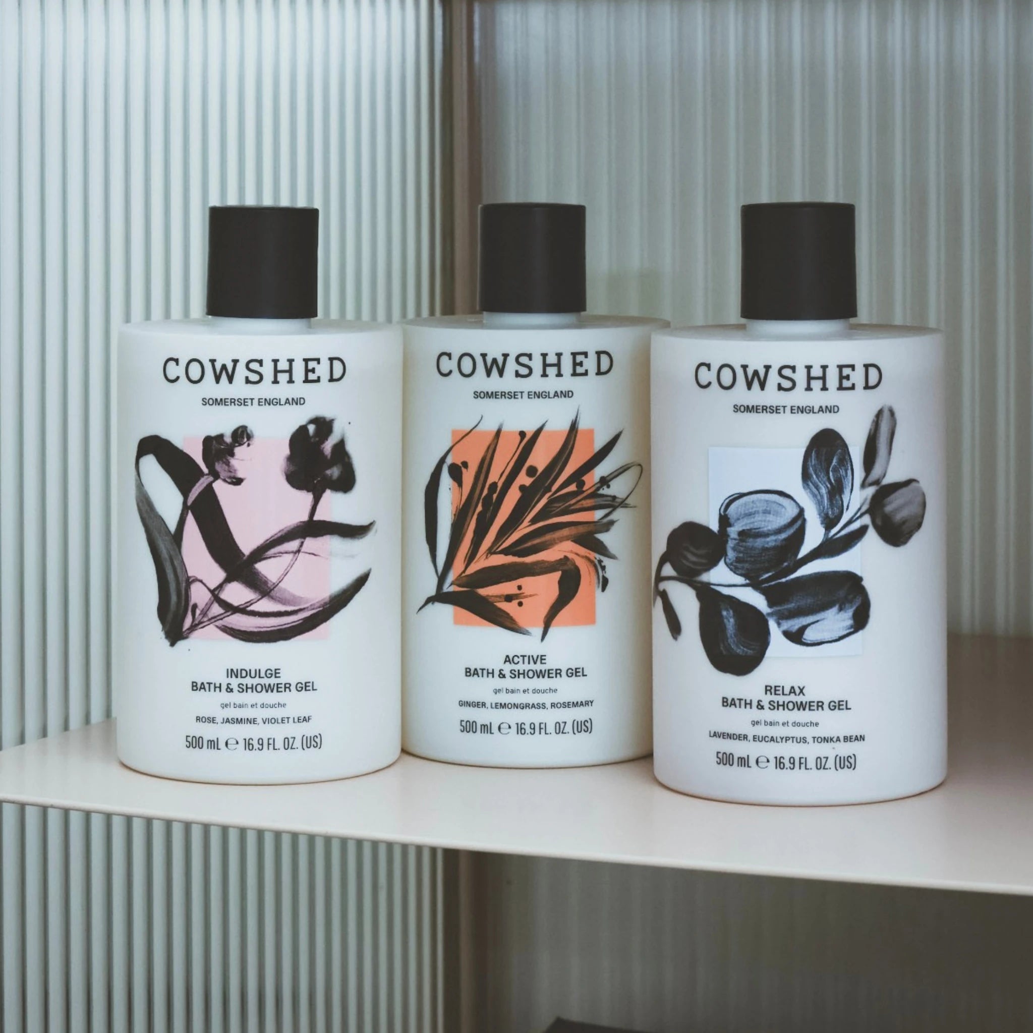 Three Cowshed bath and shower gel bottles on a shelf with a neutral background