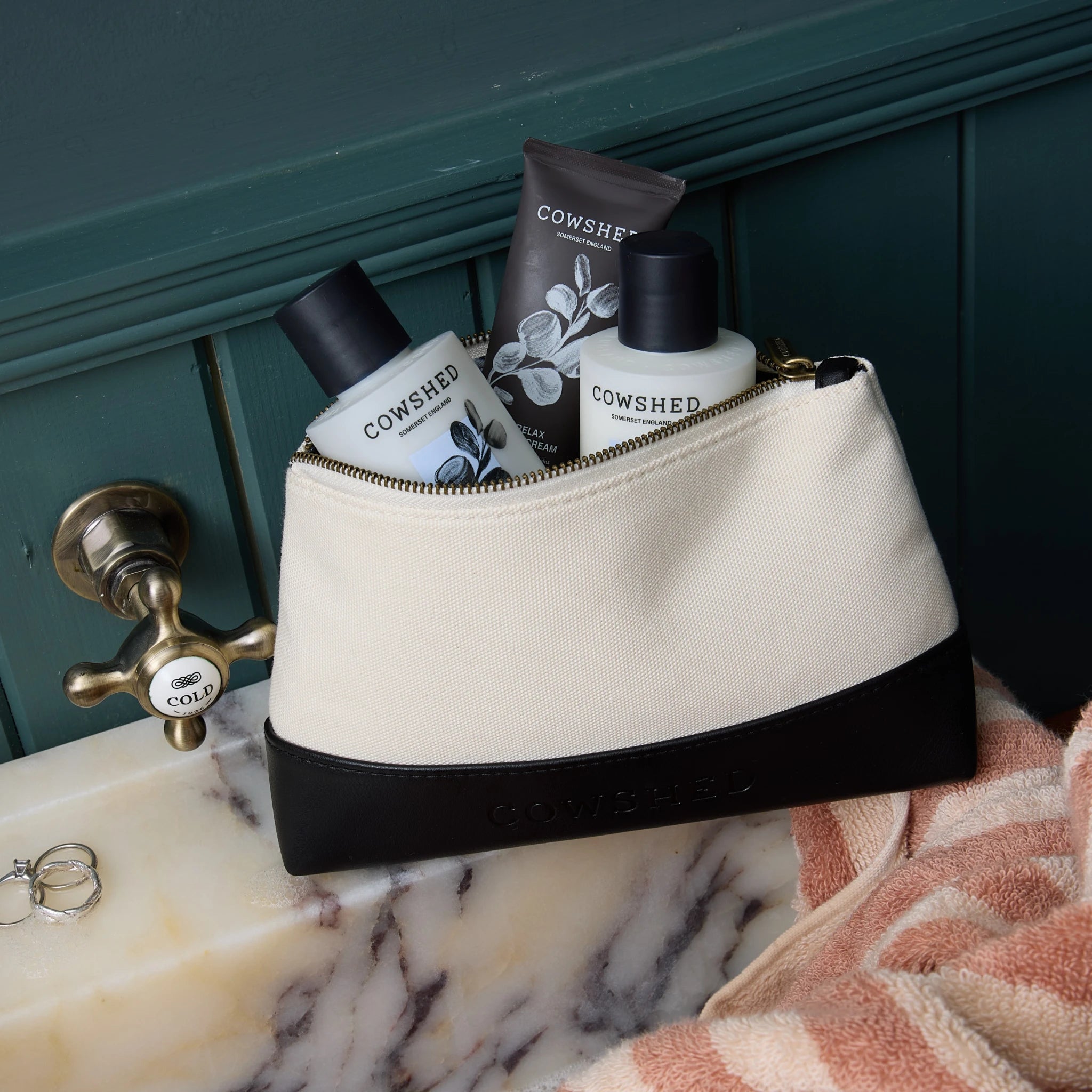 Cosmetic bag with Cowshed products on a bathroom counter