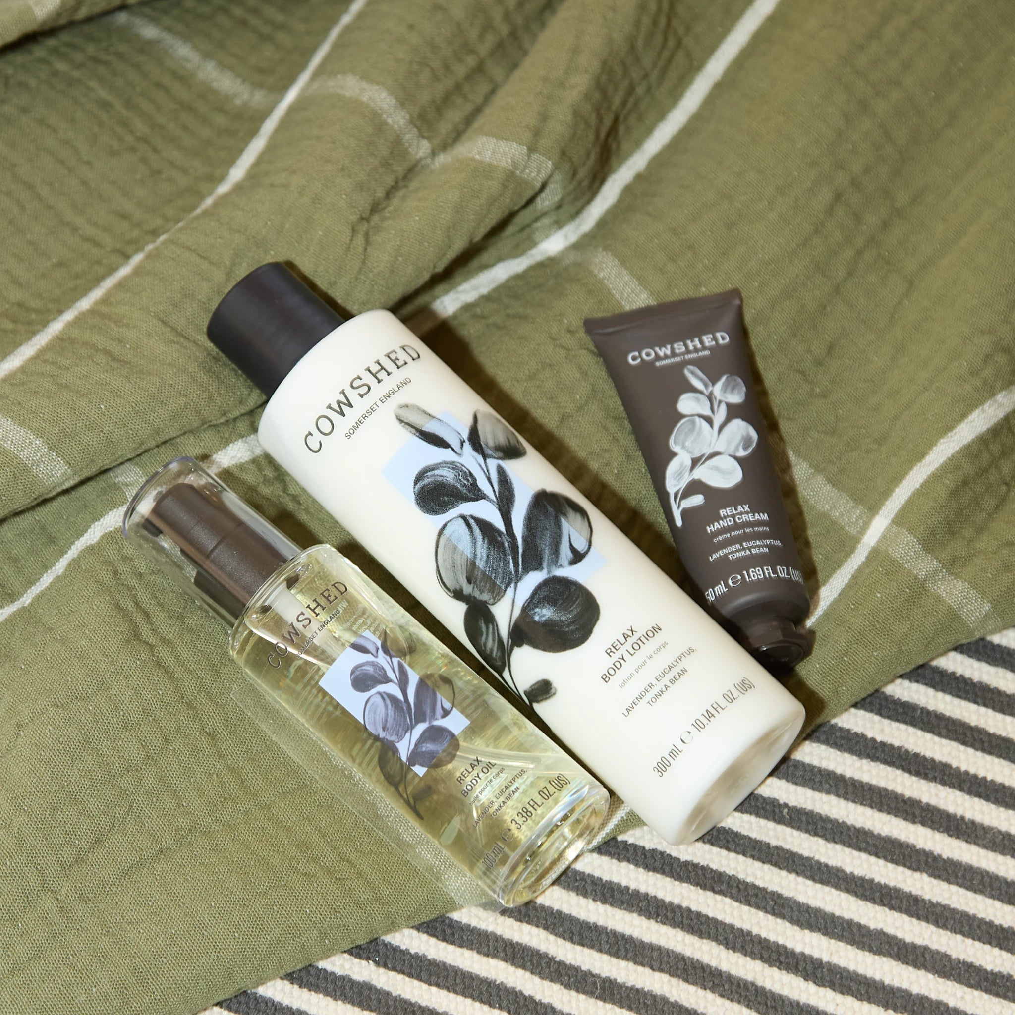 Cowshed Relax hand and bodycare products laying on a green and striped blanket