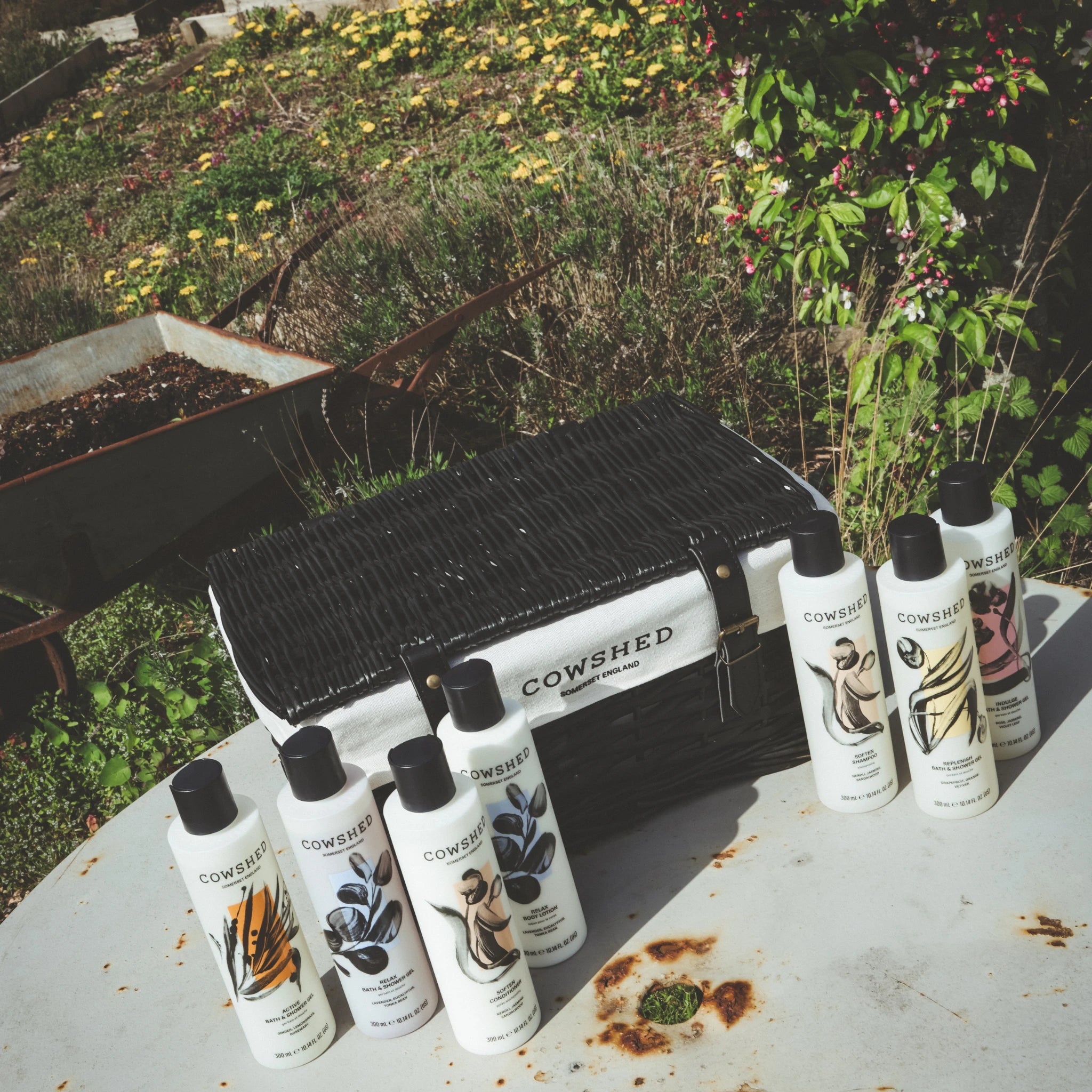 Cowshed product bottles on a rustic surface with a black toolbox in the background.