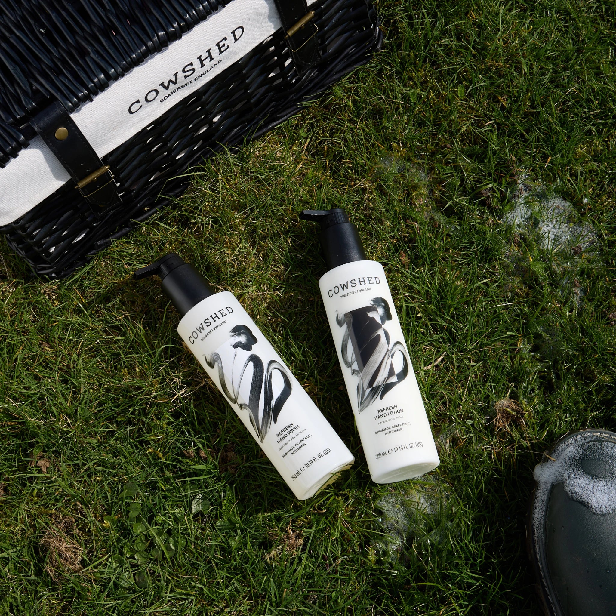 Cowshed hand care products on grass next to a hamper