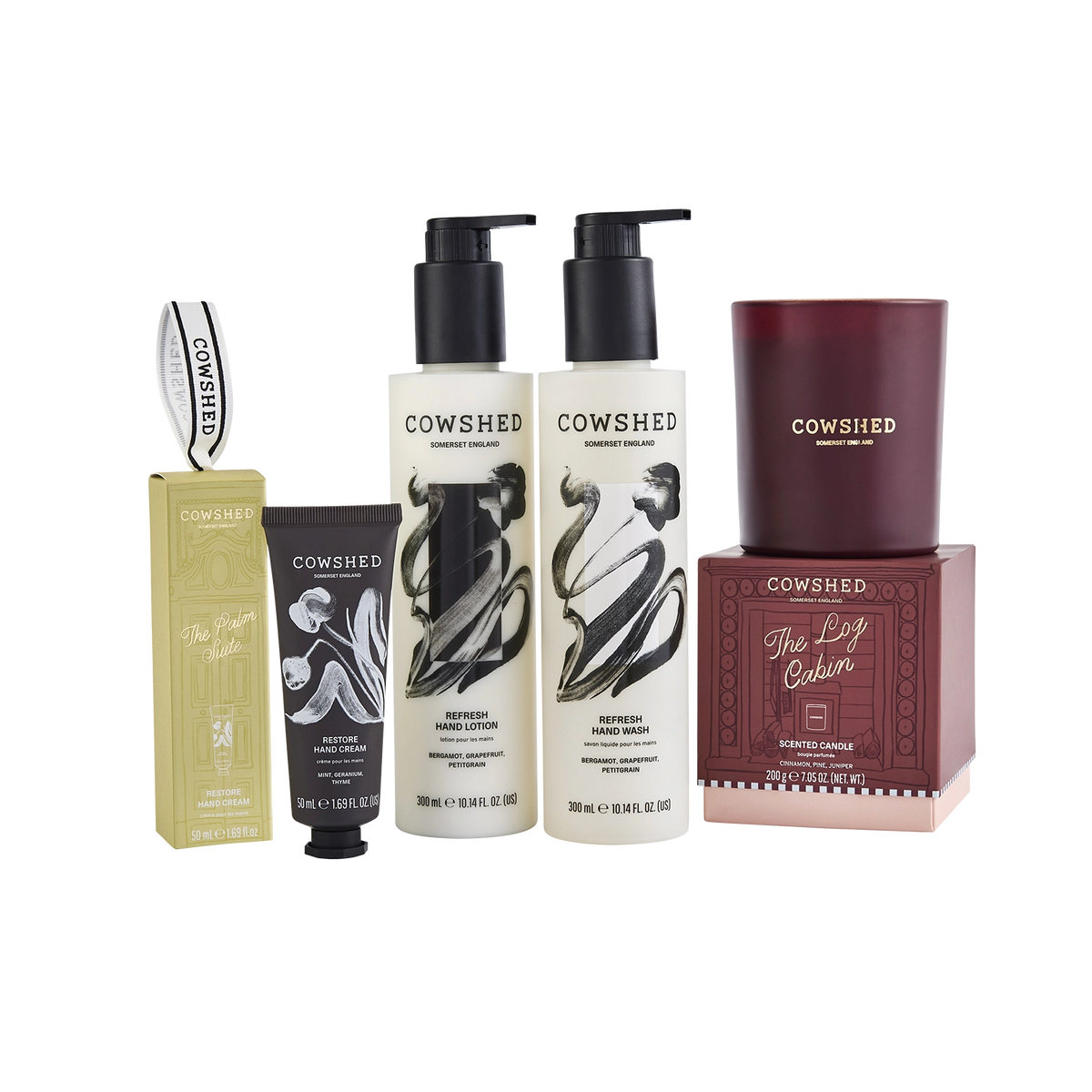 Cowshed gift set featuring two hand care bottles, a hand cream tube, a winter candle, and their respective boxes on a white background.