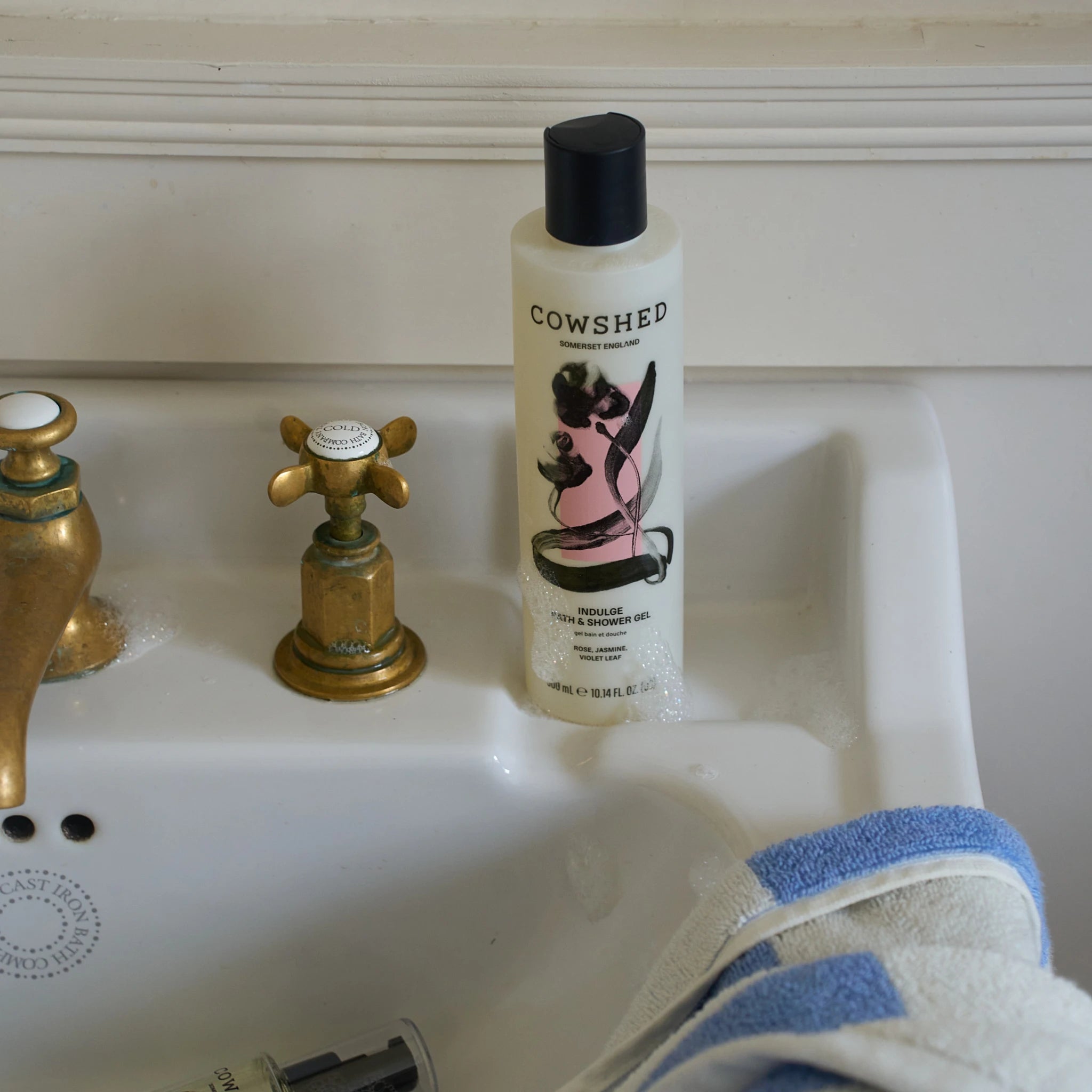 Cowshed Indulge bath and shower gel on bathroom sink with bubbles