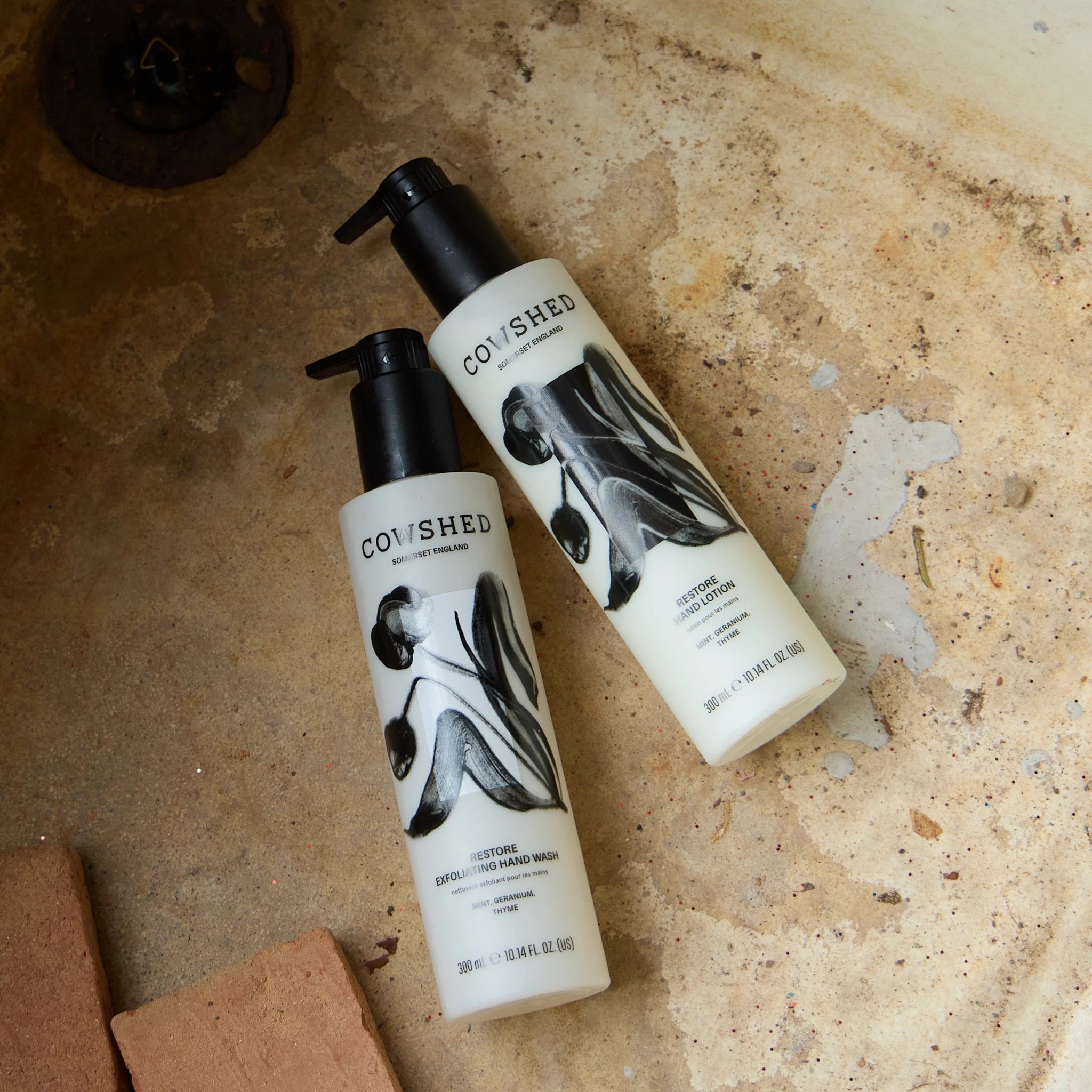 Cowshed Restore exfoliating hand wash and lotion in a garden sink