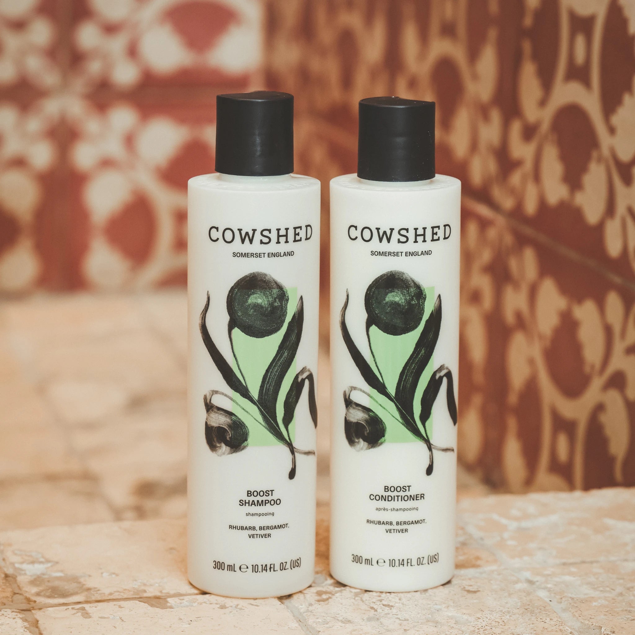 Cowshed Boost shampoo and conditioner in a red tiled shower
