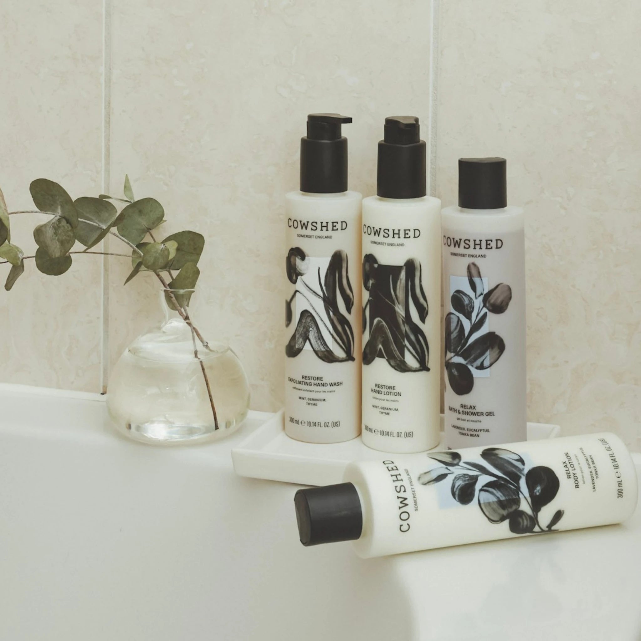 Cowshed skincare products on a bathroom counter with a plant in the background