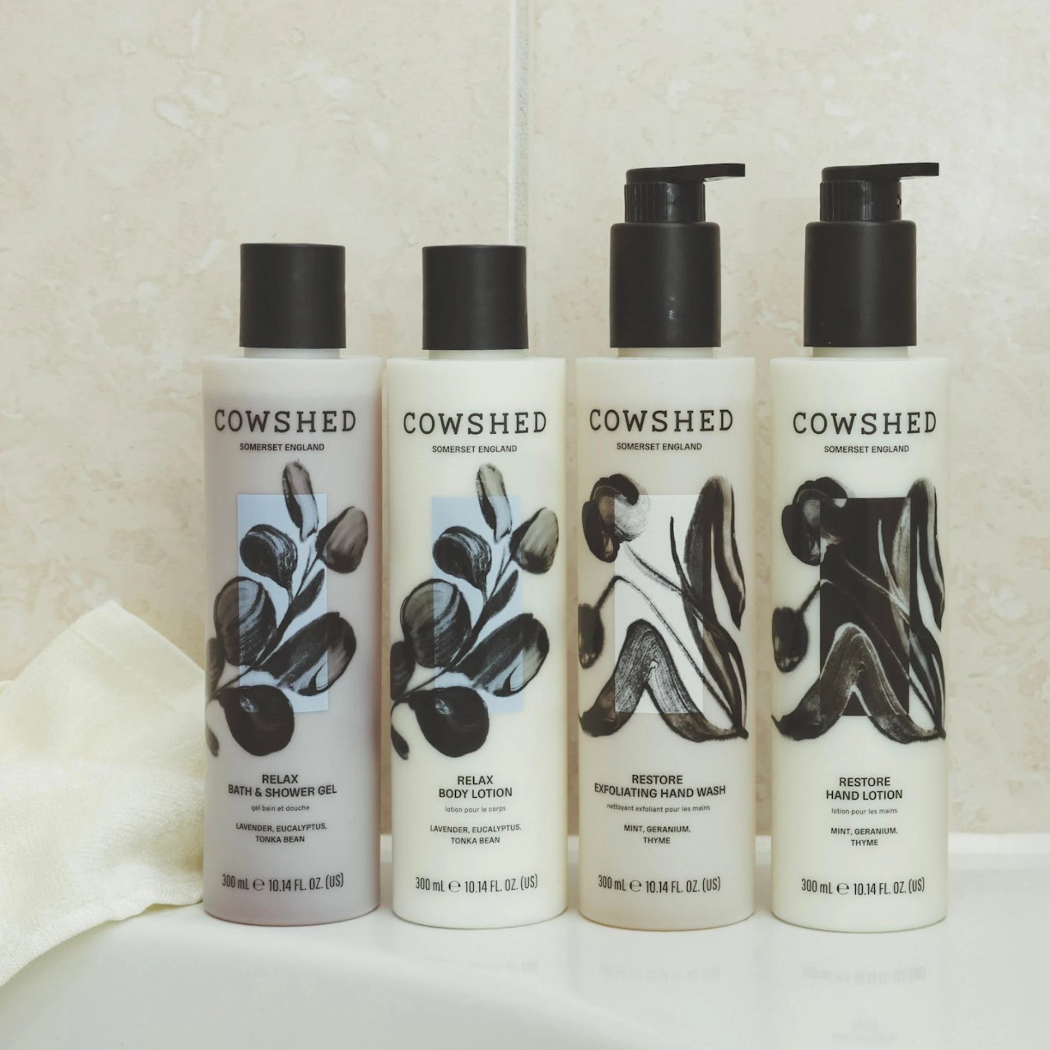 Four Cowshed product bottles on a white surface with a neutral background