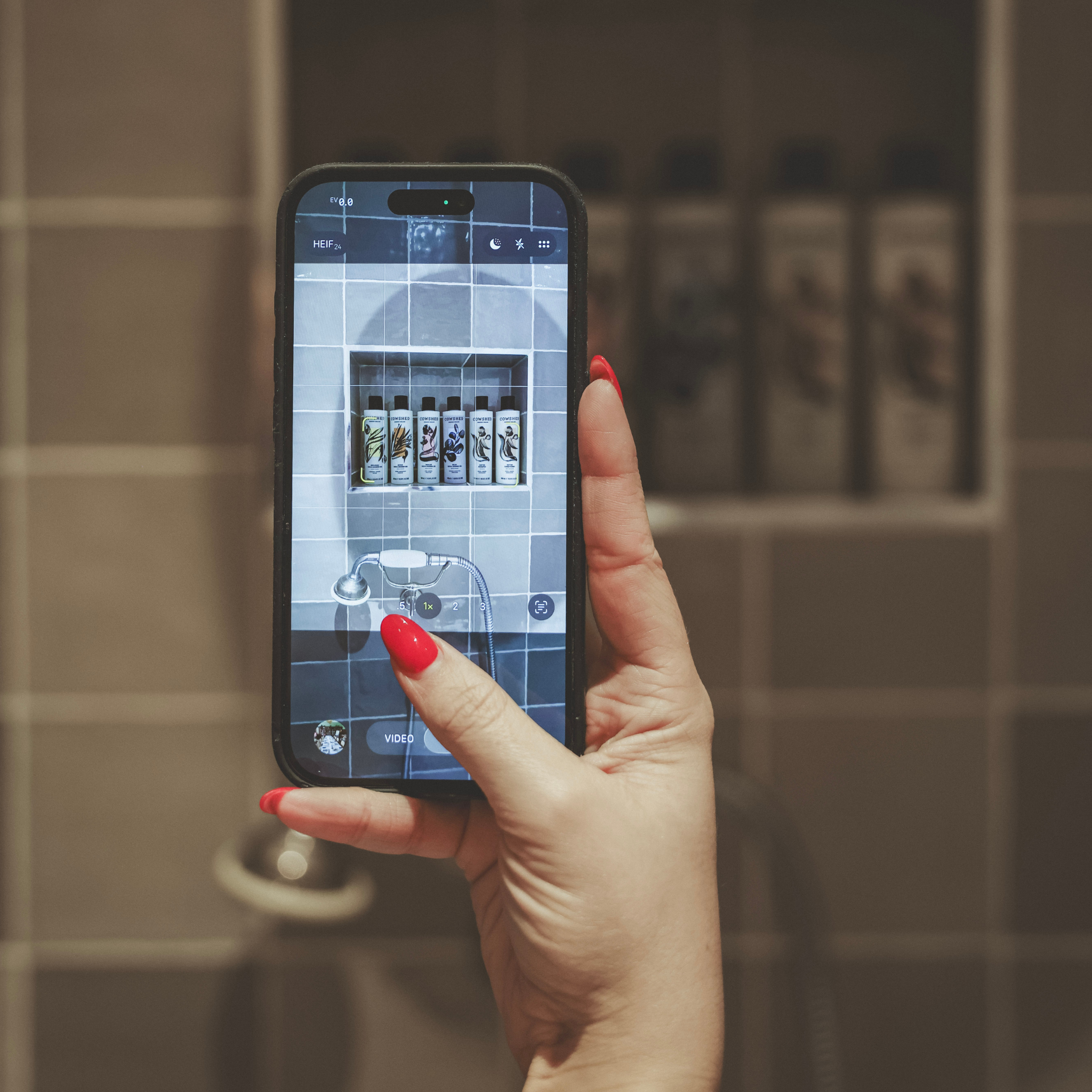 Hand holding a smartphone with a bathroom setting in the background