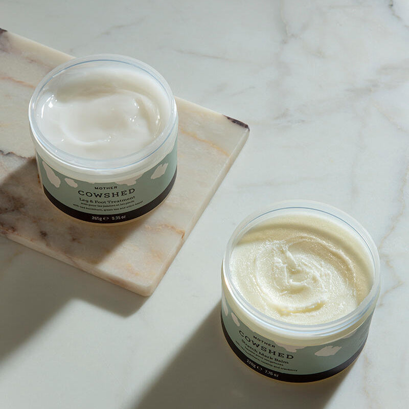 Two jars of Cowshed cream on a marble surface