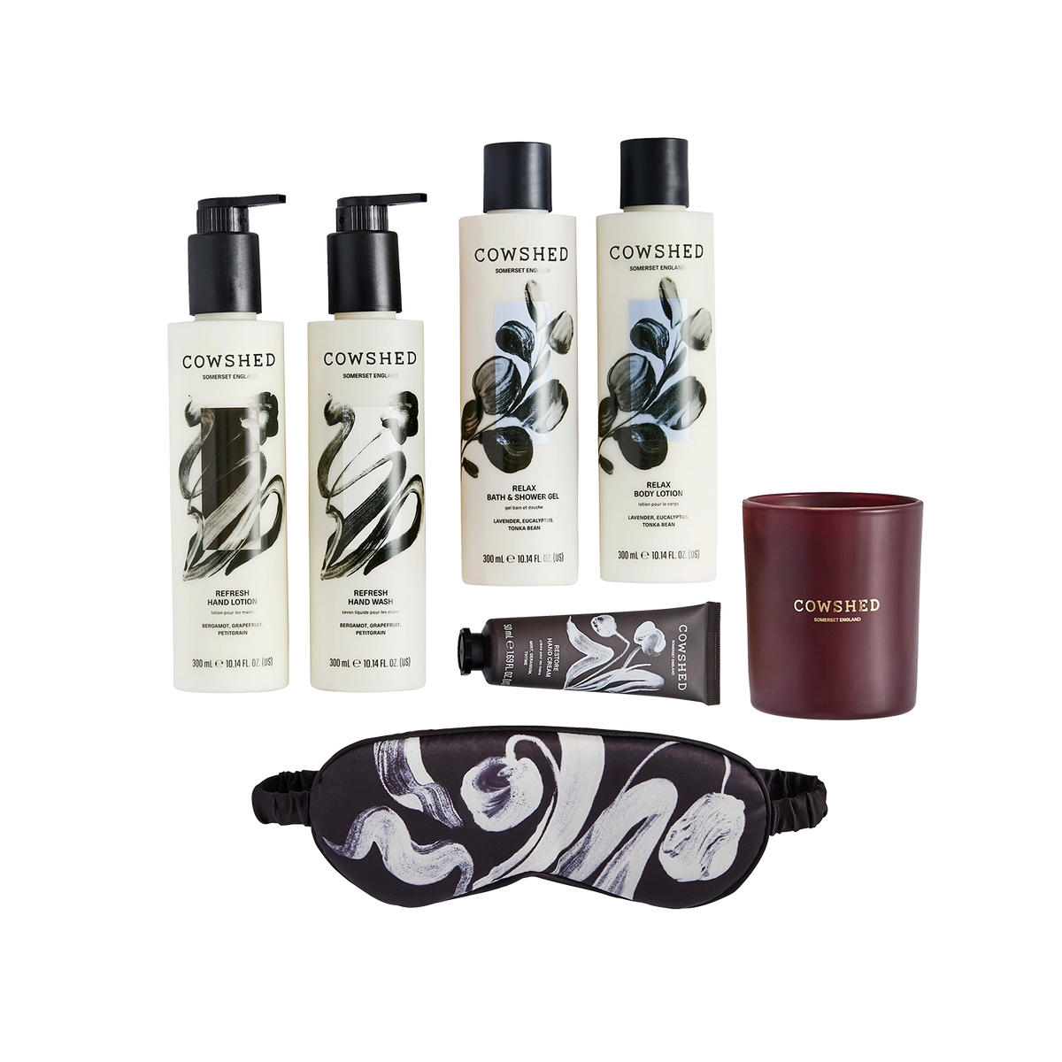 A flat lay of Cowshed products in a Christmas gift set including a winter candle, eye mask, a hand cream and hand and body care set