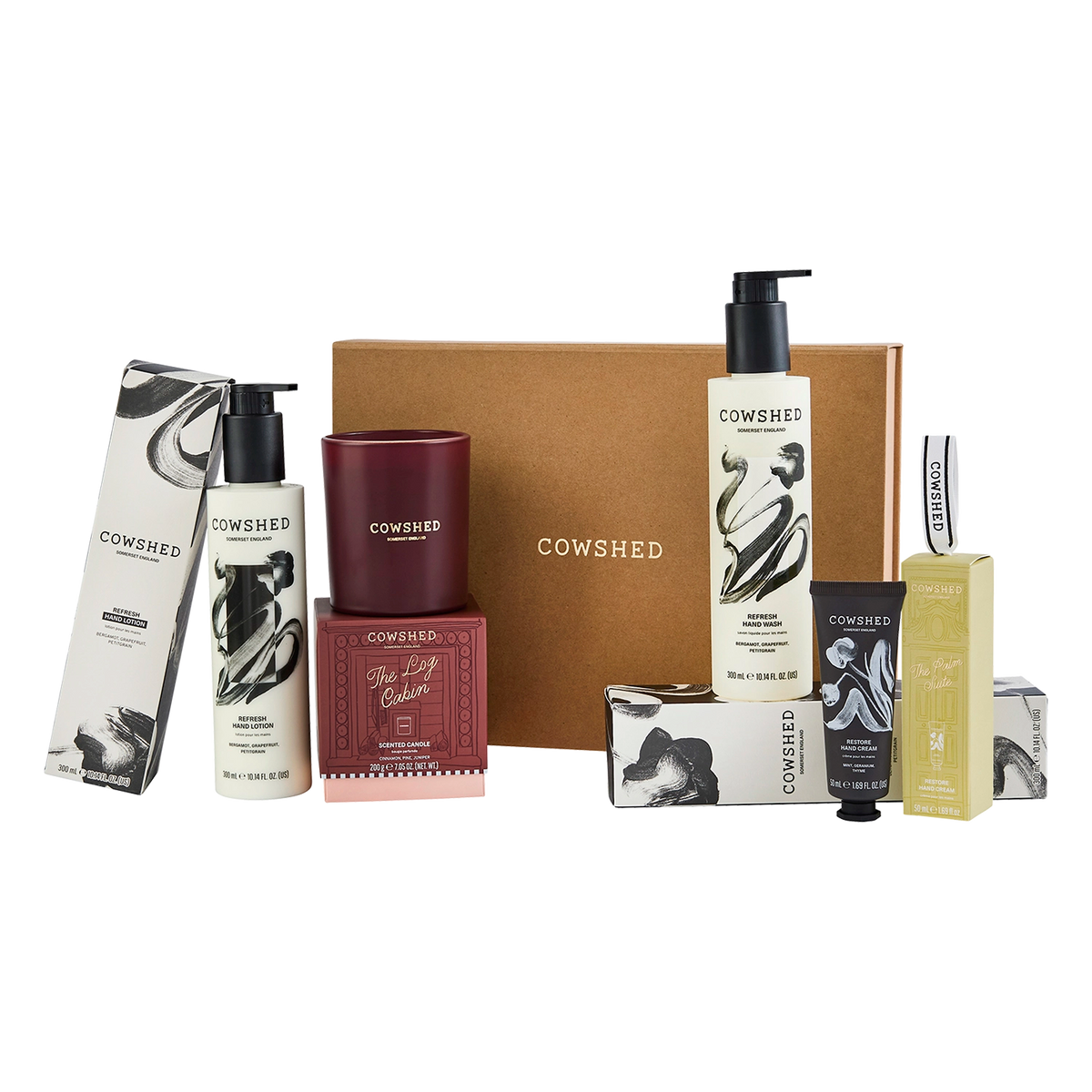 A Cowshed gift set featuring multiple home fragrance products including a candle, body wash, lotion, soap, and a large brown gift box on a white background.