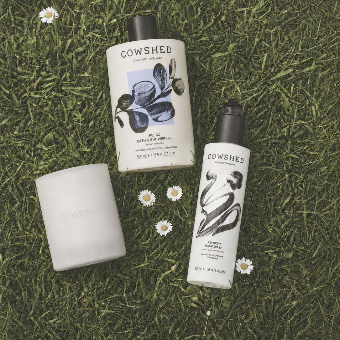 Cowshed skincare products on grass with daisies