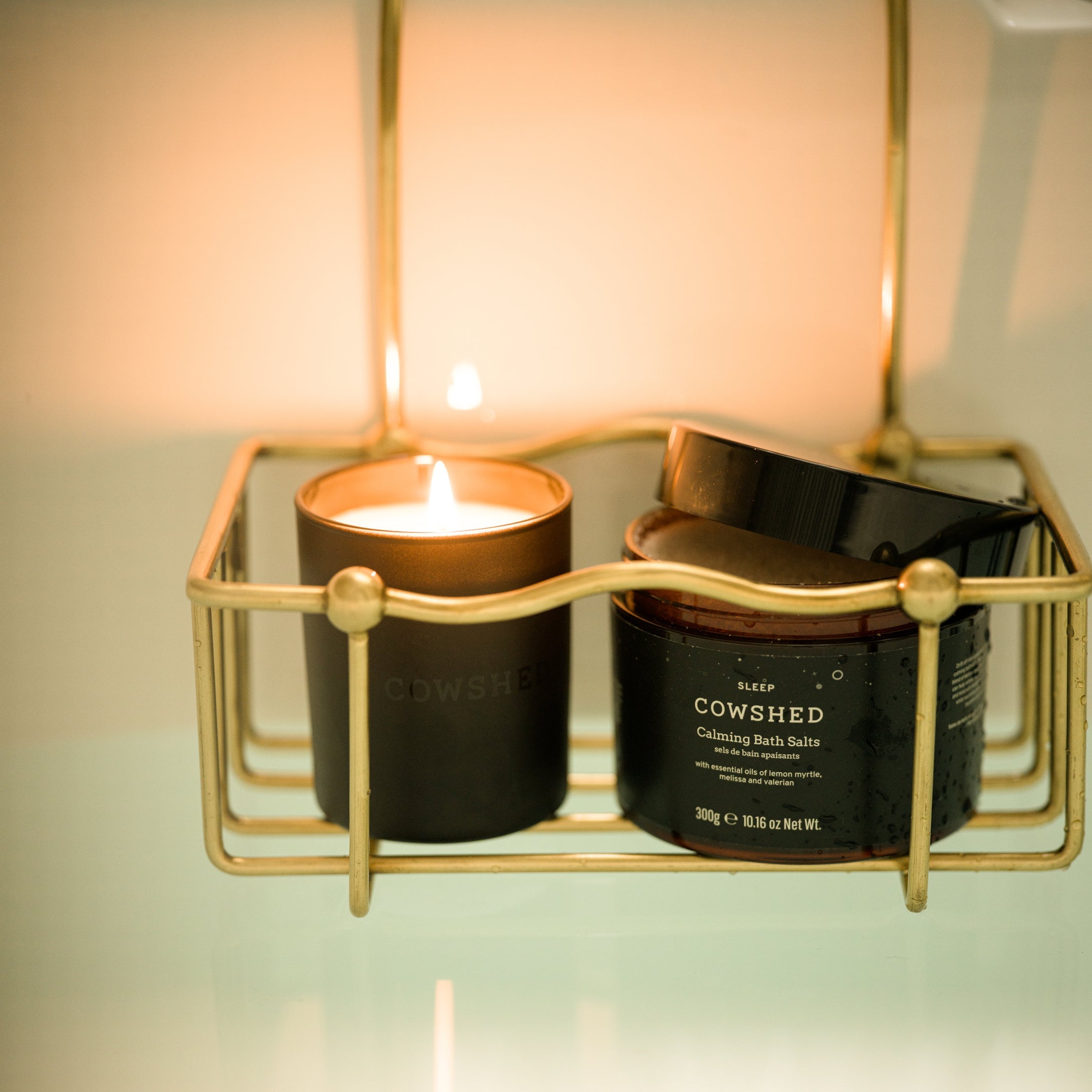 Cowshed candle and product in a gold holder with soft lighting