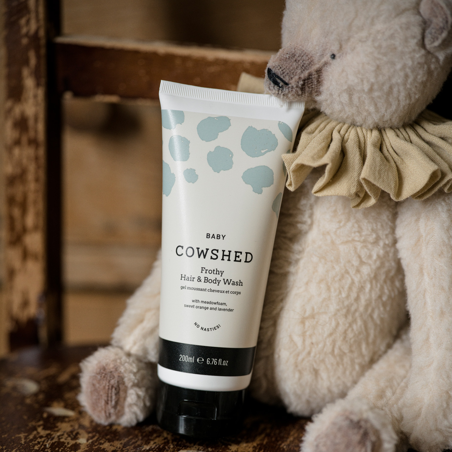 Cowshed baby hair and body wash tube with a teddy bear in the background