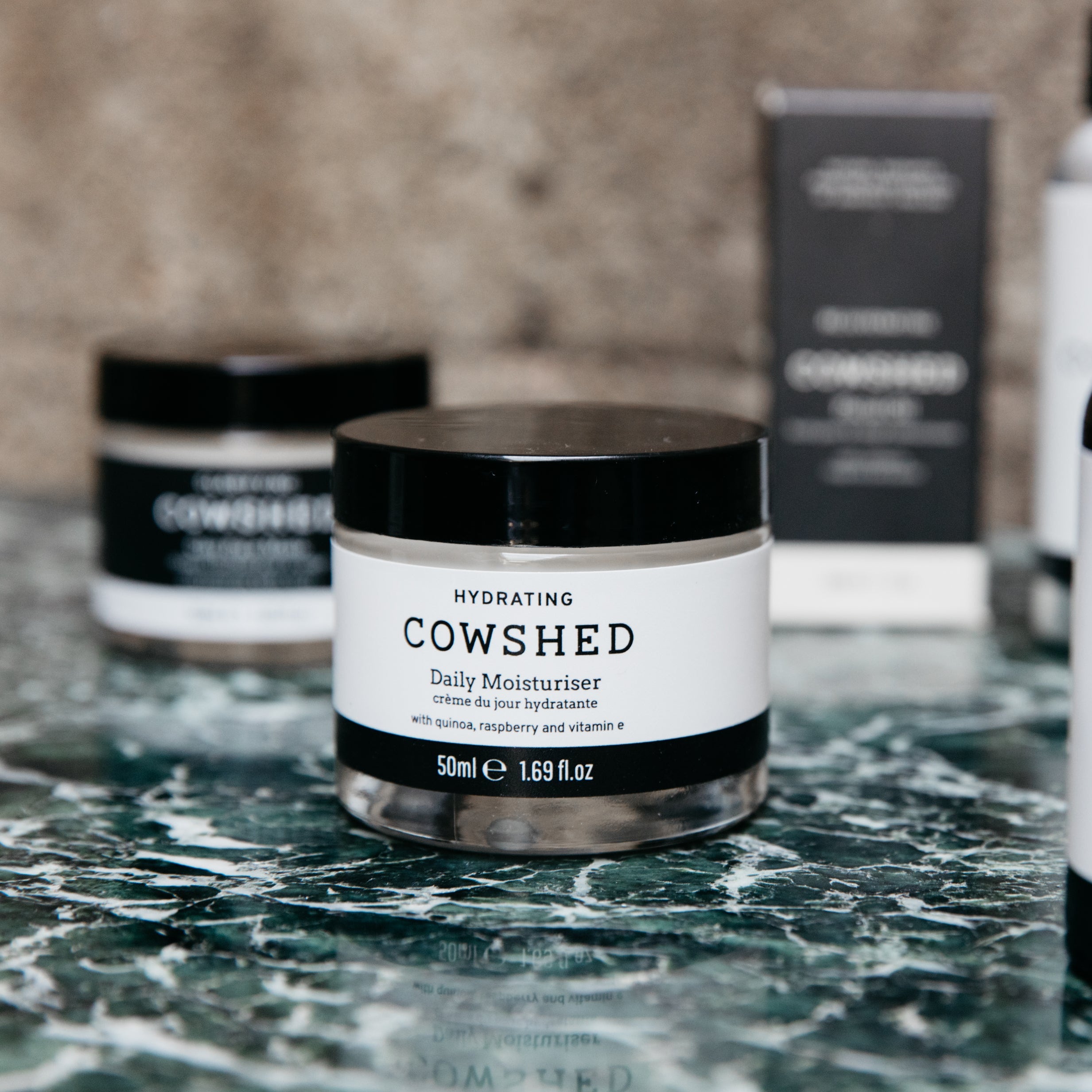 Cowshed moisturizer jar on a marble surface with a blurred background